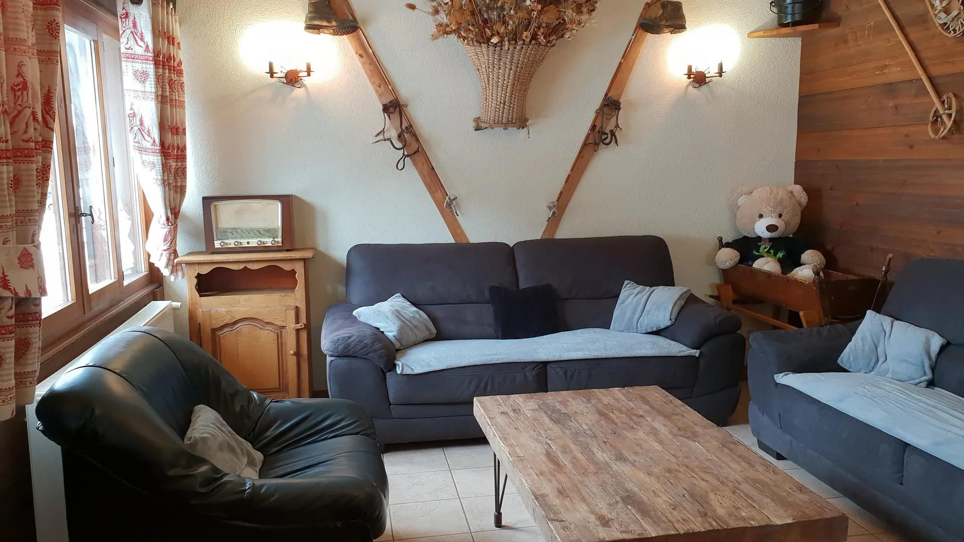 Coin salon décoré avec des vieux skis, raquettes, bâtons et ours en peluche