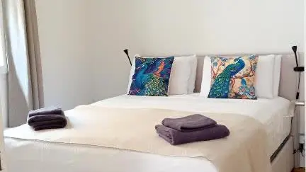 Une chambre lumineuse et épurée, offrant un grand lit douillet, une literie soignée et une atmosphère propice au repos.