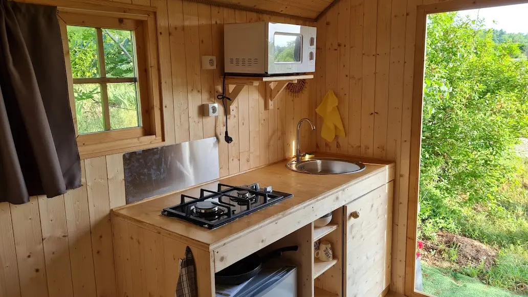 kitchenette : cafetière - bouilloire - micro-ondes - 2 feux gaz - 1 petit frigo - un évier avec jerricane d'eau pouvant être remplie dans le bloc sanitaire.