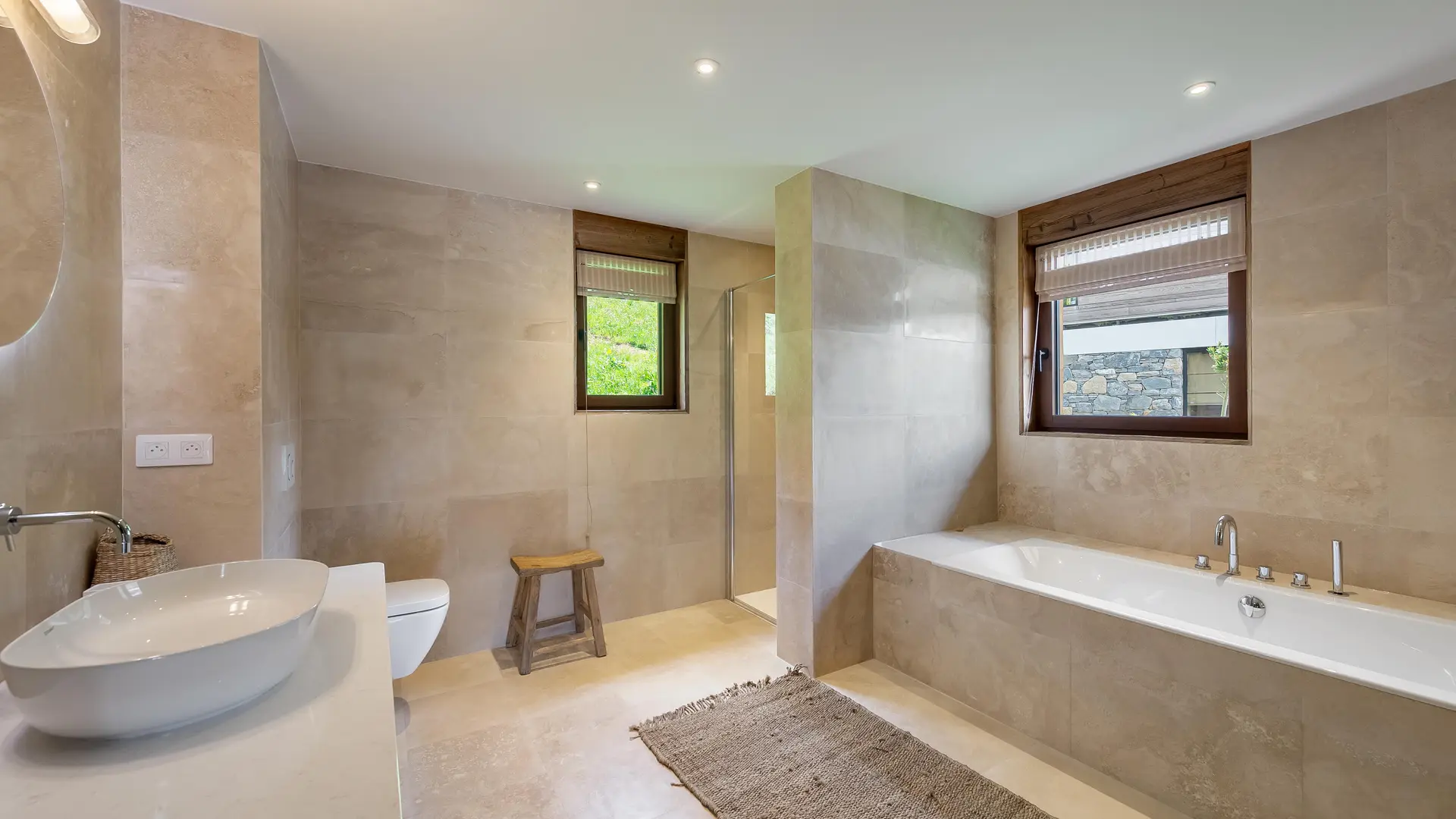 Très grande salle de bains avec baignoir et douche, toilettes, vasque et son meuble, fenêtre