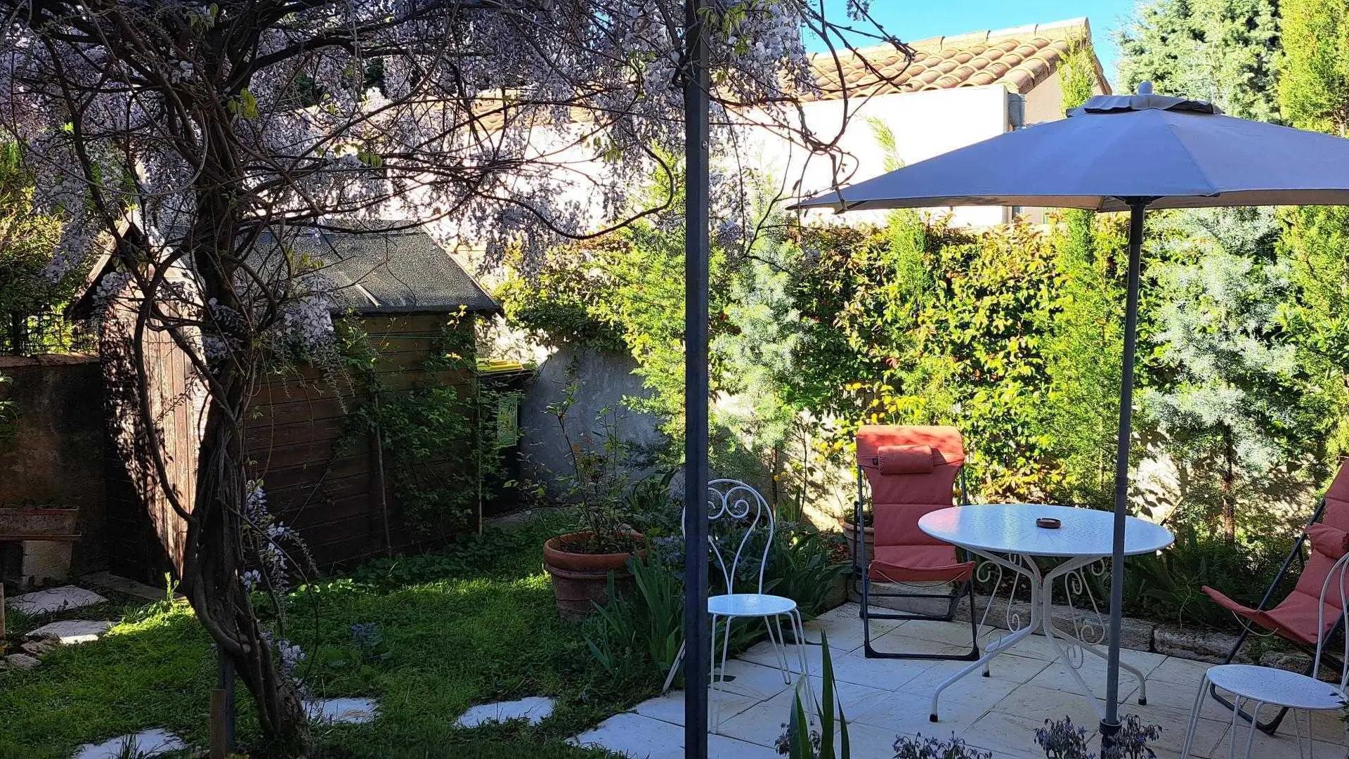 Terrasse et jardin sous la tonnelle en fleurs.
