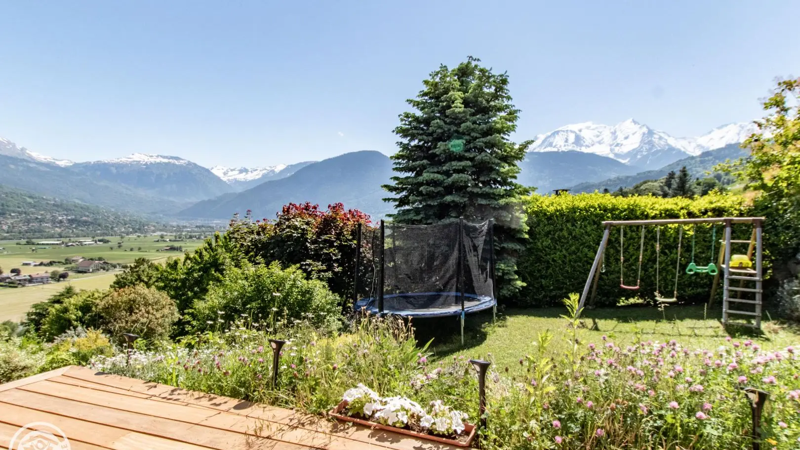 Le jardin avec trampoline, portique et sauna panoramique.