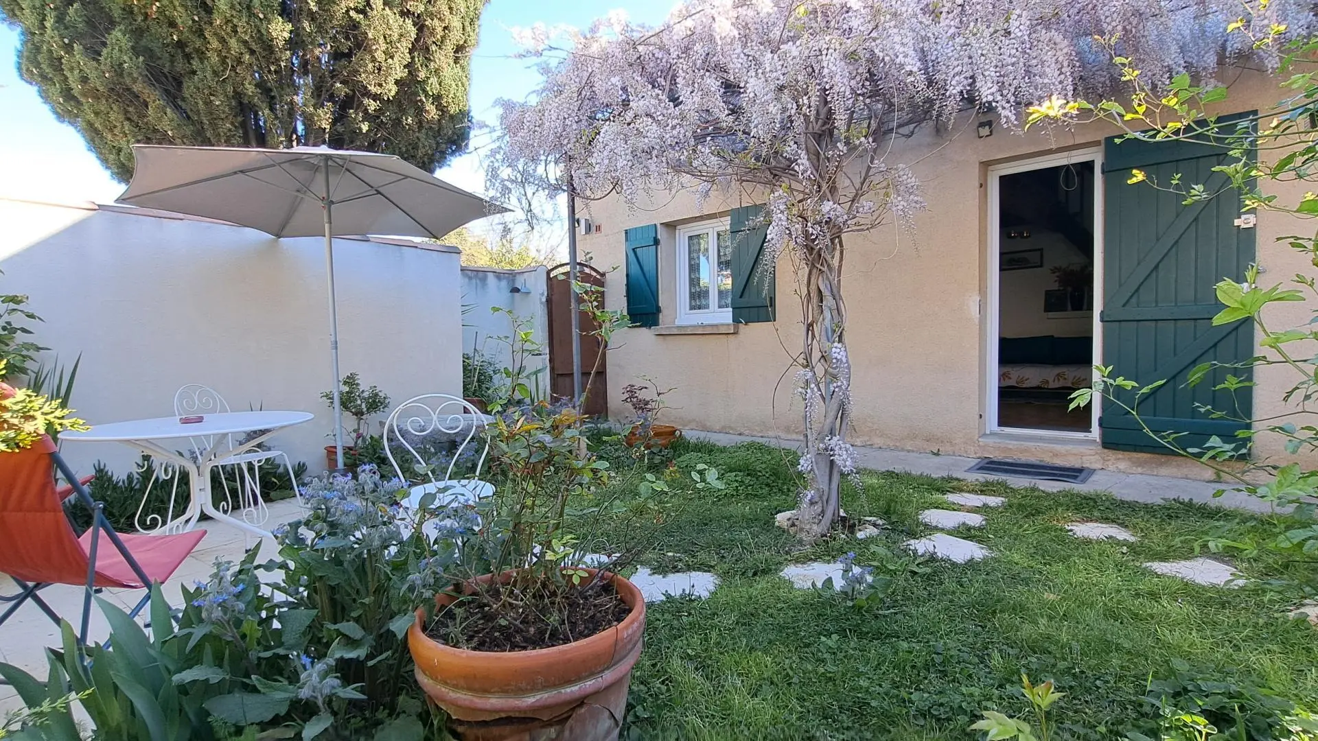 Tonnelle Glycine en fleurs sur l'entrée de L'Oustau dei Aucèus avec sa terrasse.