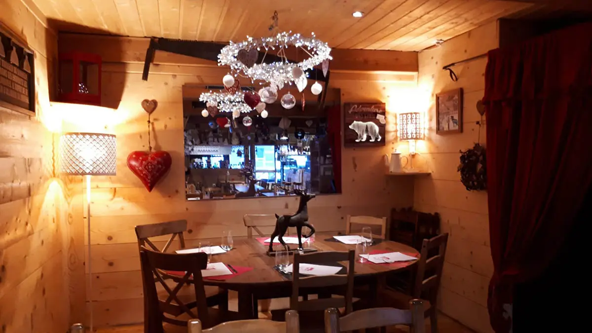 Salle intérieure du restaurant, tables et chaises, ambiance lumineuse et confortable, décoration montagne