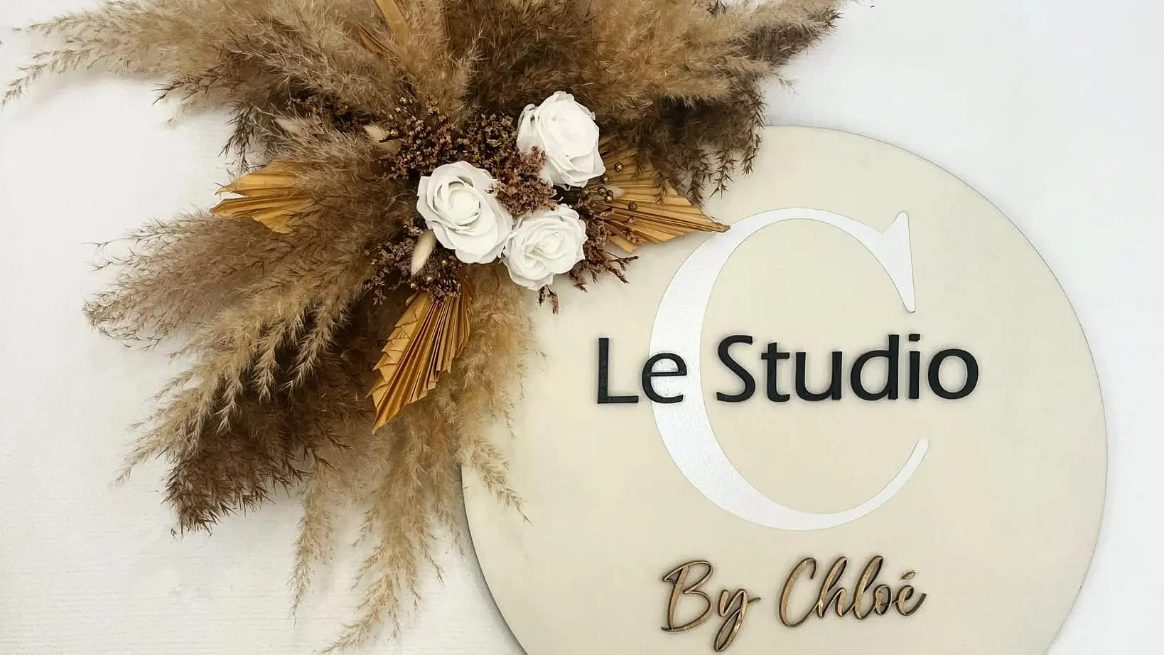 Nom de la boutique inscrit sur une plaque avec des fleurs séchées