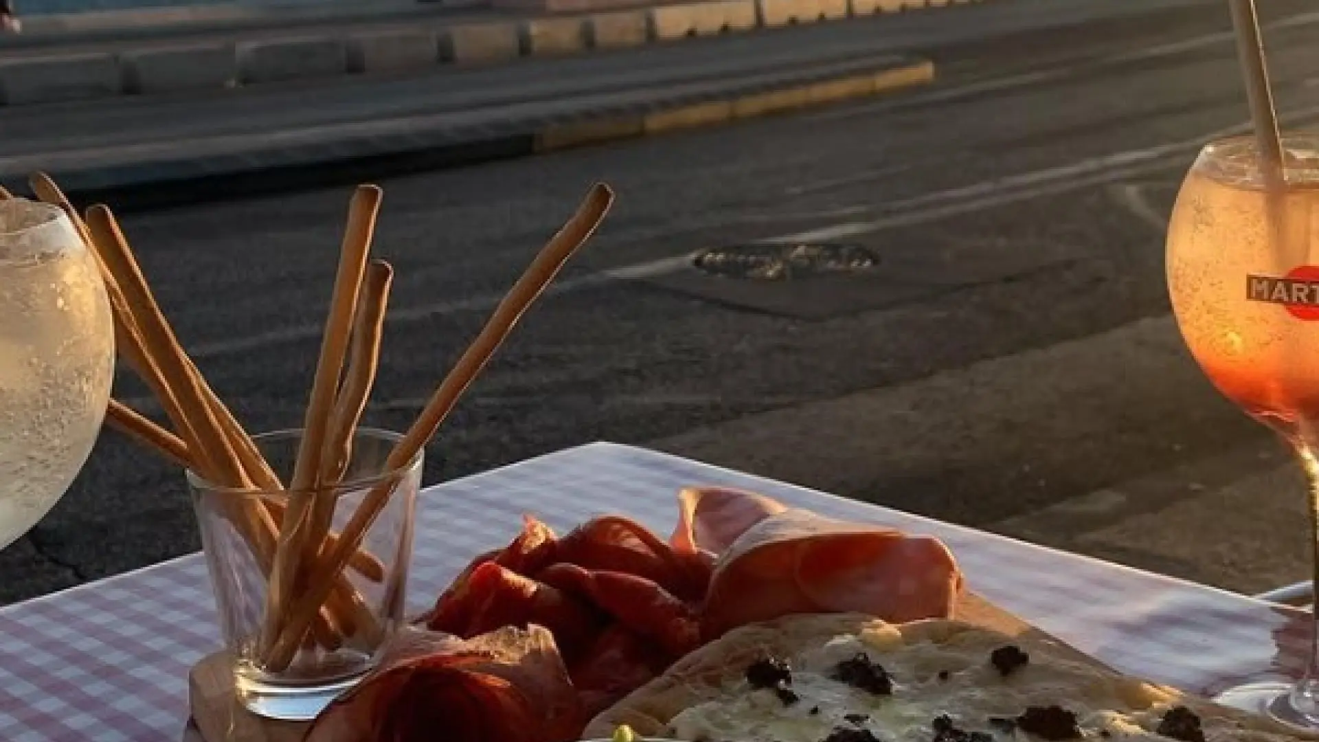 table garnie avec produits italien en terrasse et coucher de soleil