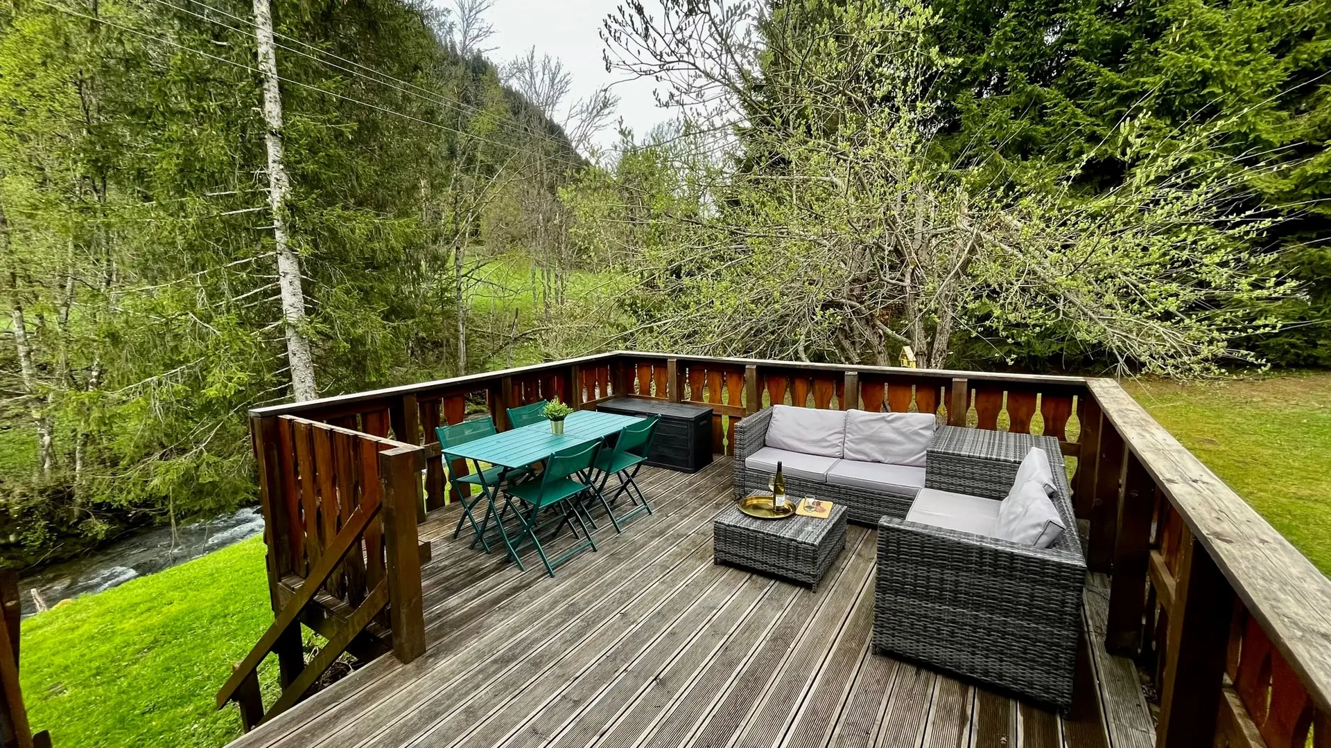 Grande terrasse avec coin salon et table à manger surplombant la rivière