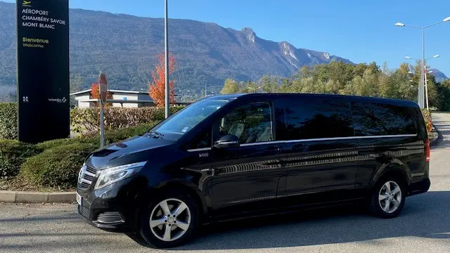 Véhicule noir garé devant un panneau à l'aéroport de Chambéry