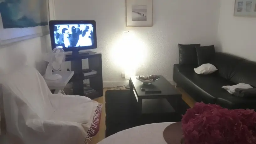 Un coin salon avec une télévision sur un meuble à gauche, et un canapé à droite.