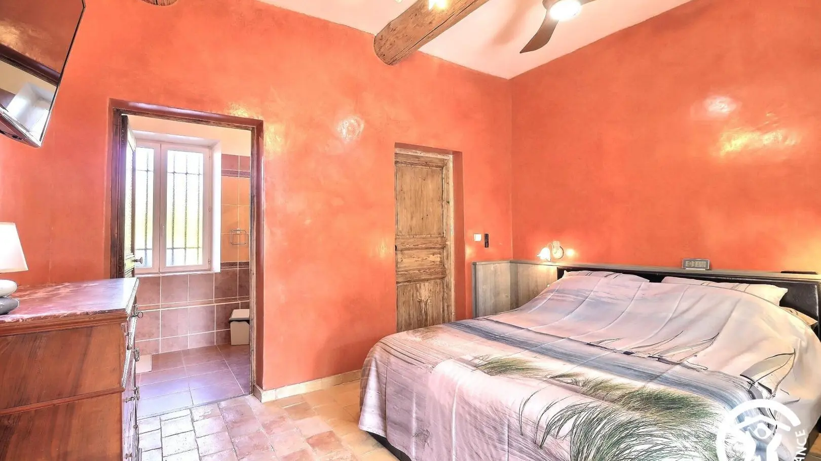 Chambre équipée d'un ventilateur de plafond et d'une télévision.