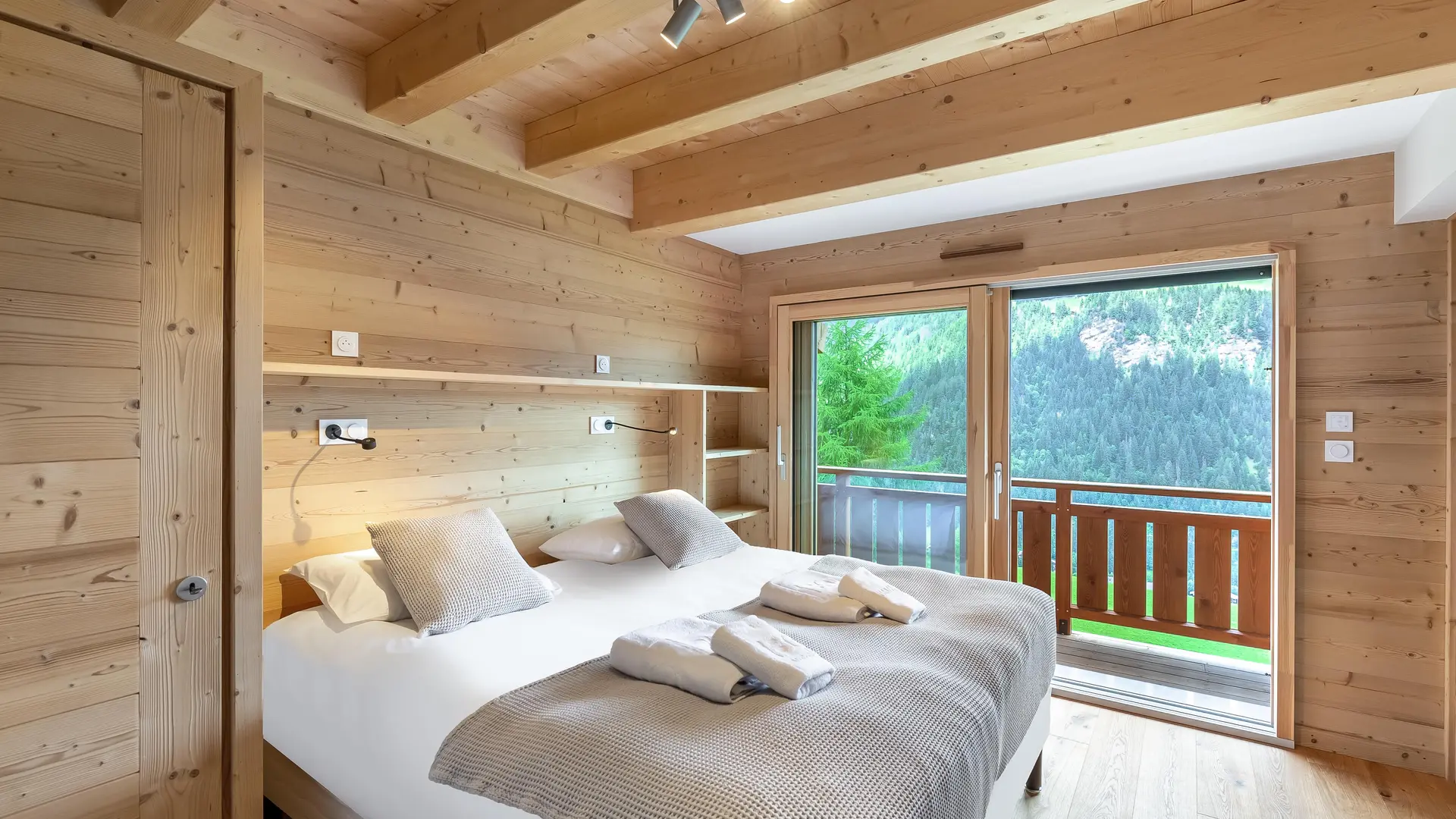 Chambre double, poutres apparentes, porte fenêtre donnant accès à un balcon, vue sur les montagnes