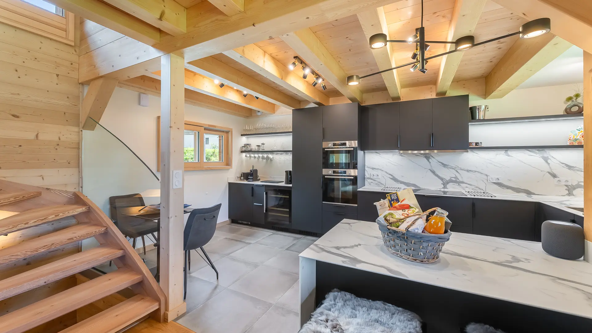 Cuisine moderne toute équipée, mélange de bois et de marbre, espace repas, grand ilot