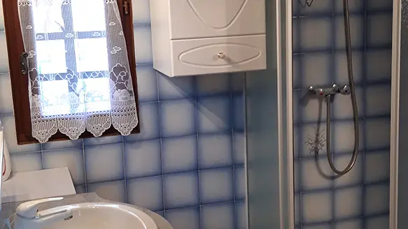 Tiled bathroom with shower tray, sink, parquet flooring and window