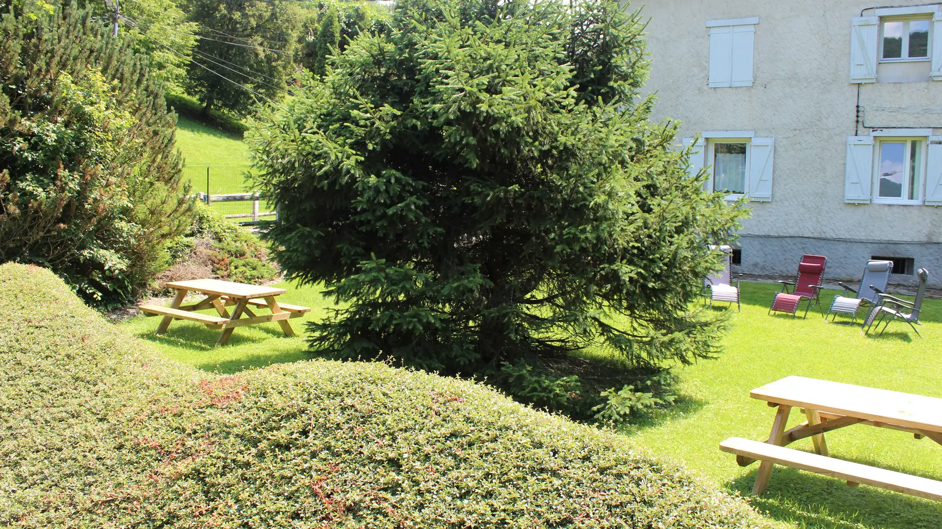 Dans le jardin, on trouve deux tables de pique-nique et des chaises longues.