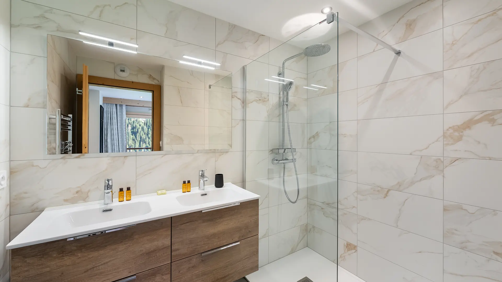 Salle de bains avec double vasque et son meuble, grand miroir et douche à l'italienne