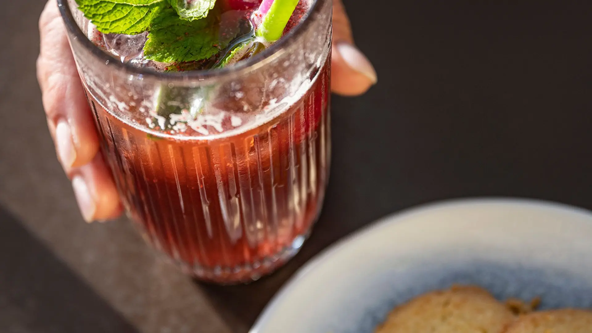 boisson te,ue dans la main et gateau salée dans une assiette gros plan