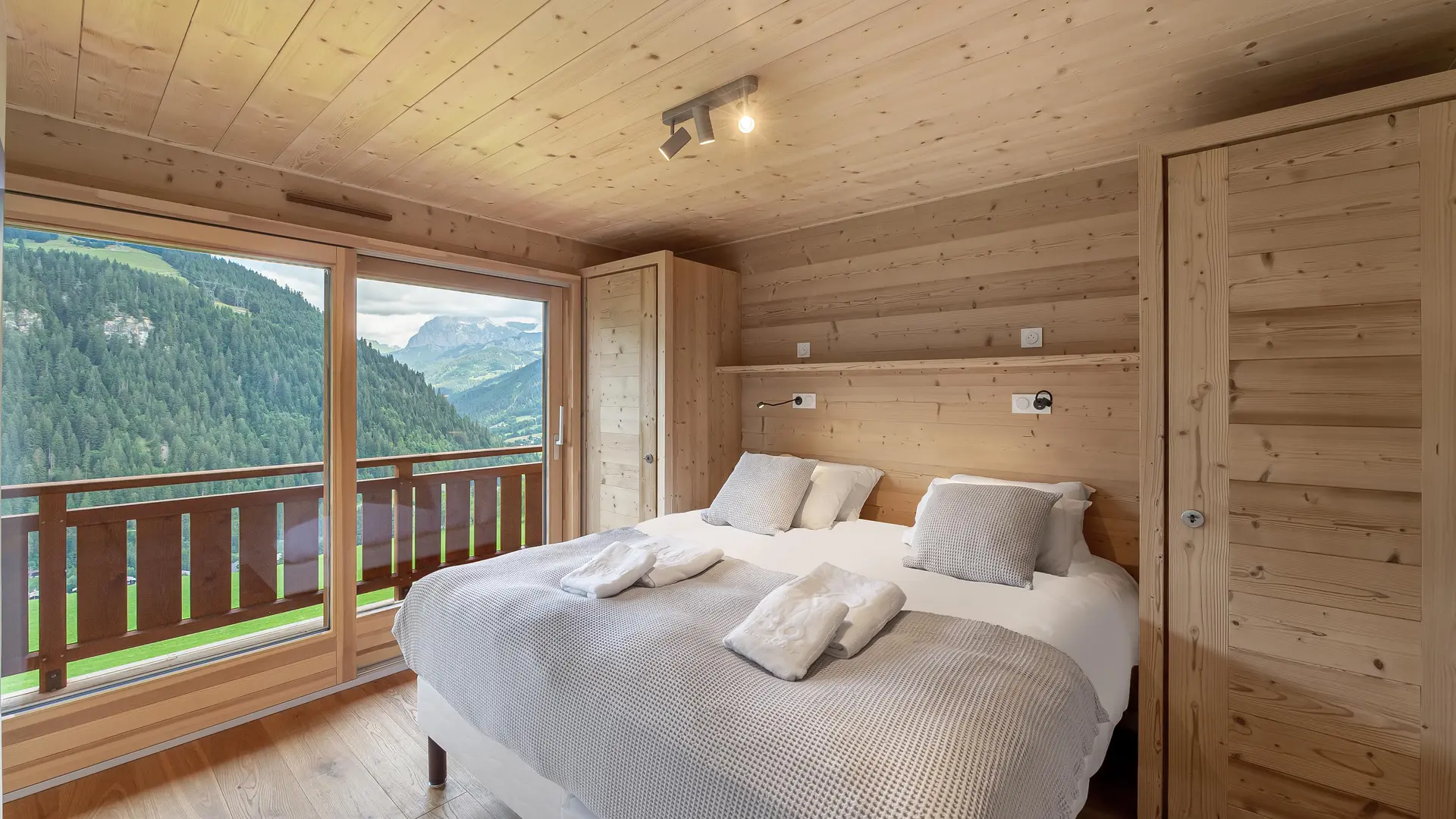 Chambre double avec grande baie vitrée donnant accès au balcon et vue sur la montagne