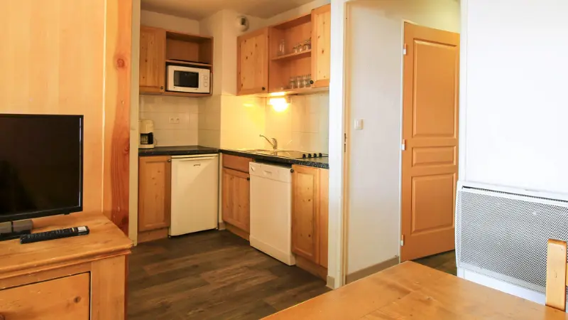 Apartment living room, dining table, kitchenette with electric hobs, dishwasher, microwave