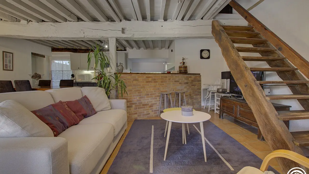 Espace salon avec le charme du bois et de la brique, et l'accès à la mezzanine.