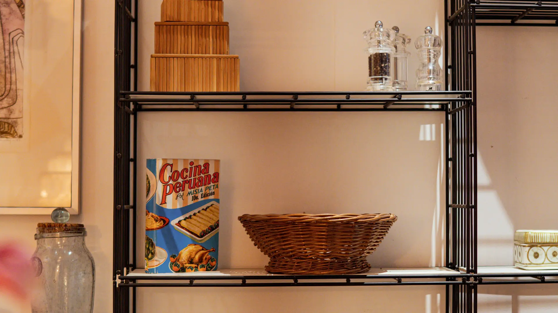 Une étagère métallique expose un mélange charmant d’objets décoratifs, de céramiques et de livres anciens.