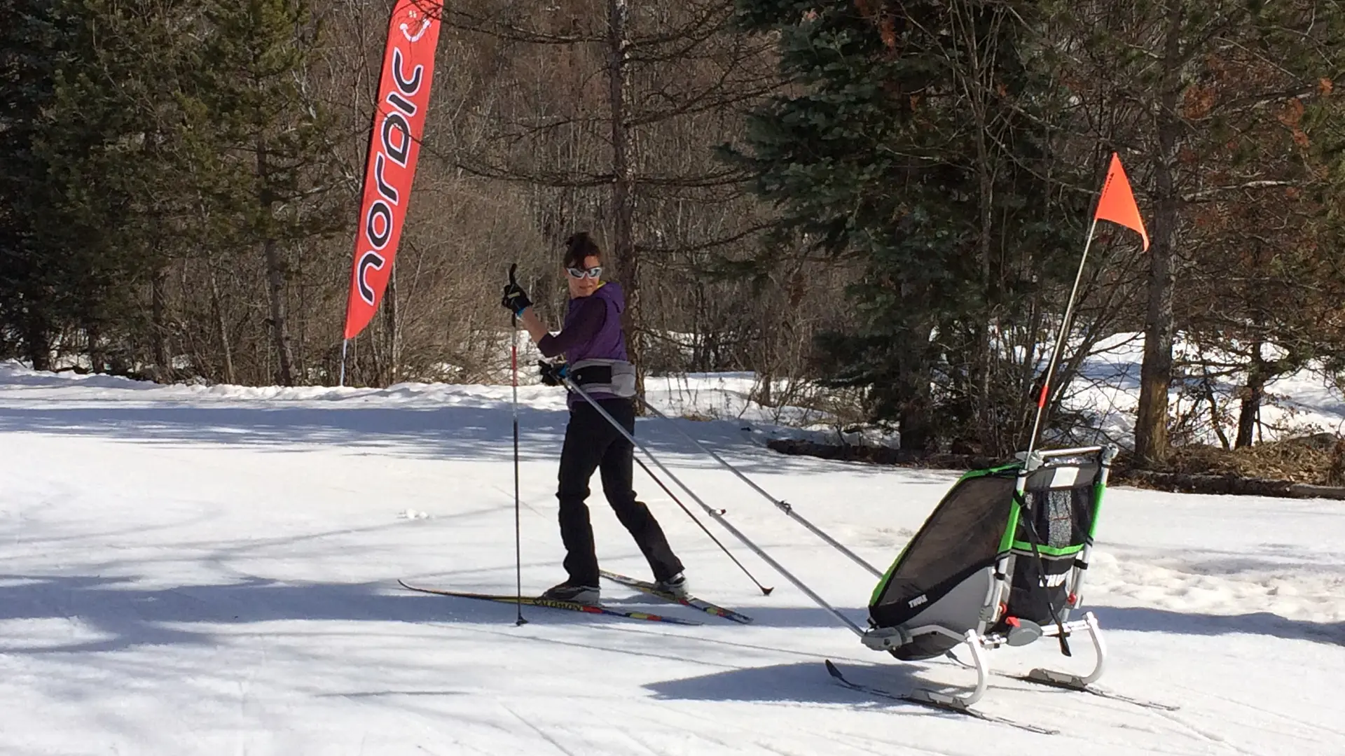 Une maman tire à skis une pulka où dort son bébé