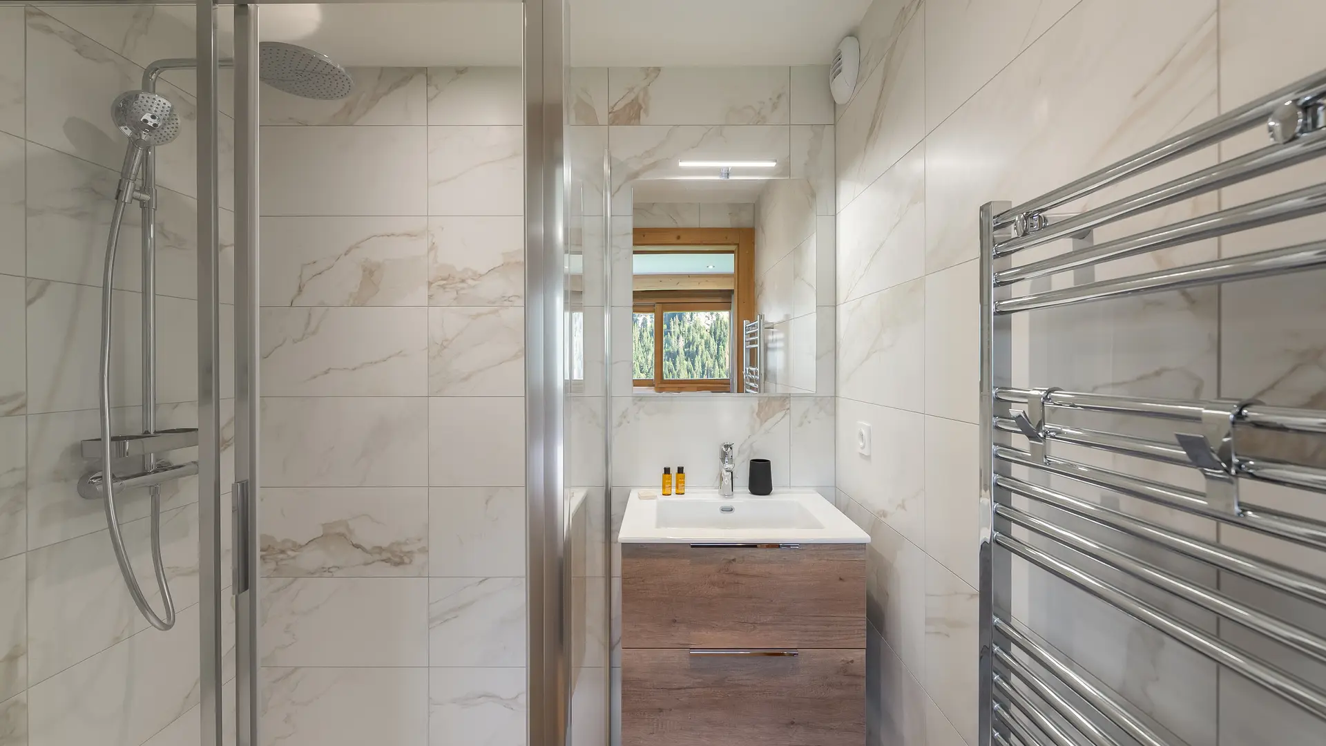 Salle de bains avec douche, vasque simple et son meuble, miroir, sèche serviettes et fenêtre