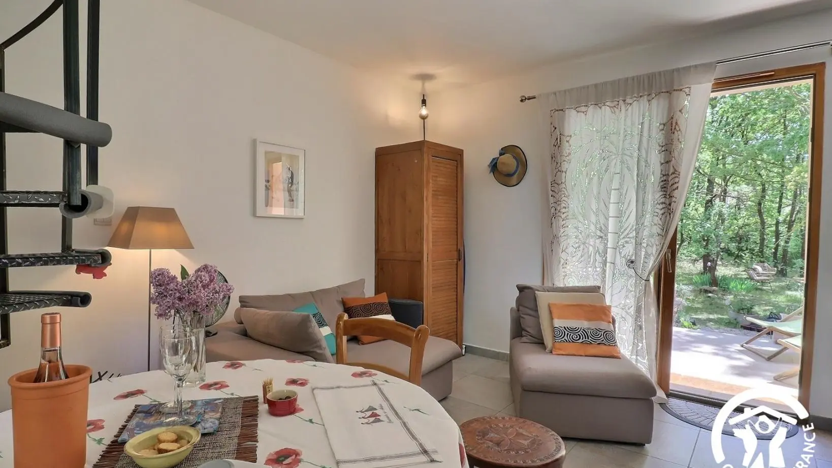 Entrée dans le séjour par la terrasse . A gauche, sur la photo, canapé et fauteuil , meuble de rangement.