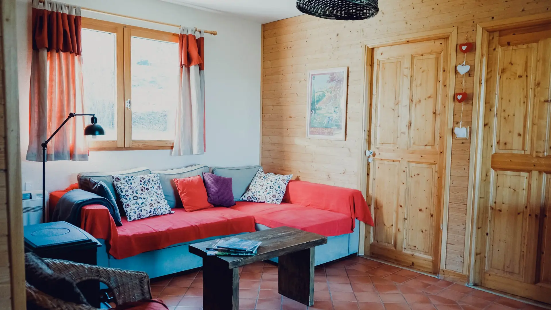 Ce salon se compose d'un canapé d’angle, d’une table basse, au fond une fenêtre laissant entrer la lumière naturelle.