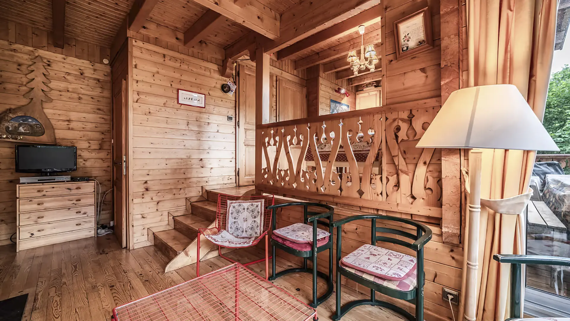Fauteuils, table basse, meuble avec télévision, escalier qui mène à la cuisine