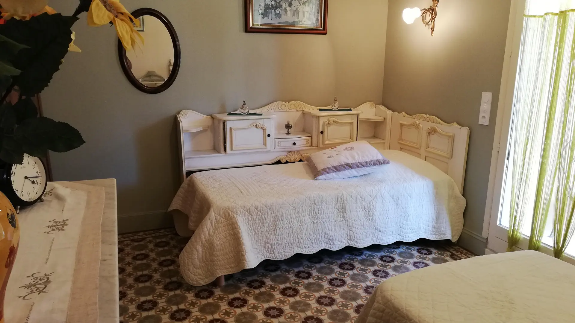 Une chambre chaleureuse aux meubles patinés et au sol à carreaux anciens, idéale pour un séjour reposant.