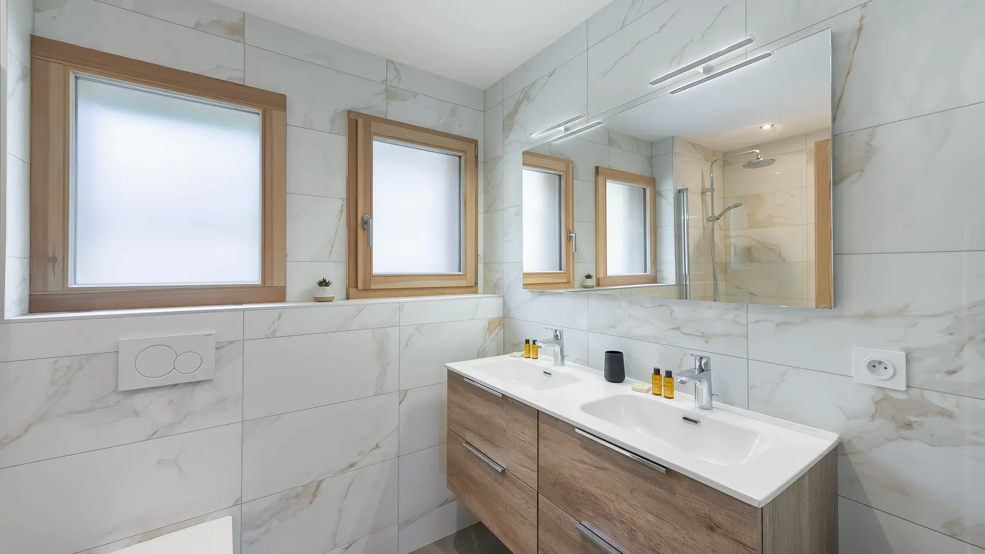 Salle de bains avec double vasque et son meuble, grand miroir, deux fenêtres
