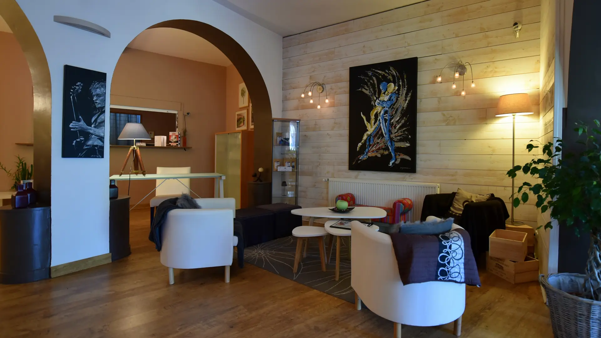 Trois fauteuils confortables vous invitent à un moment de détente, éclairés par deux appliques murales et une lampe sur pied