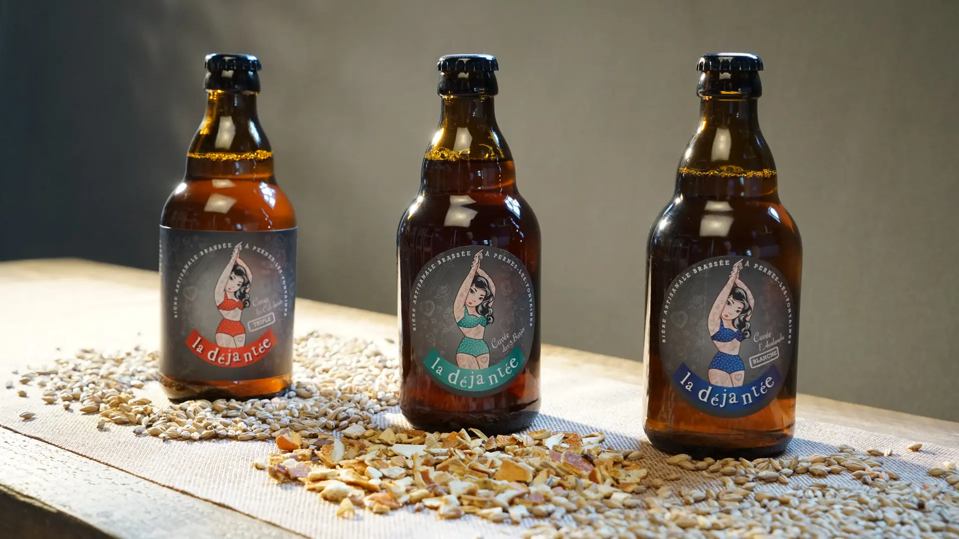 Trio de bières artisanales sur lit de céréales.