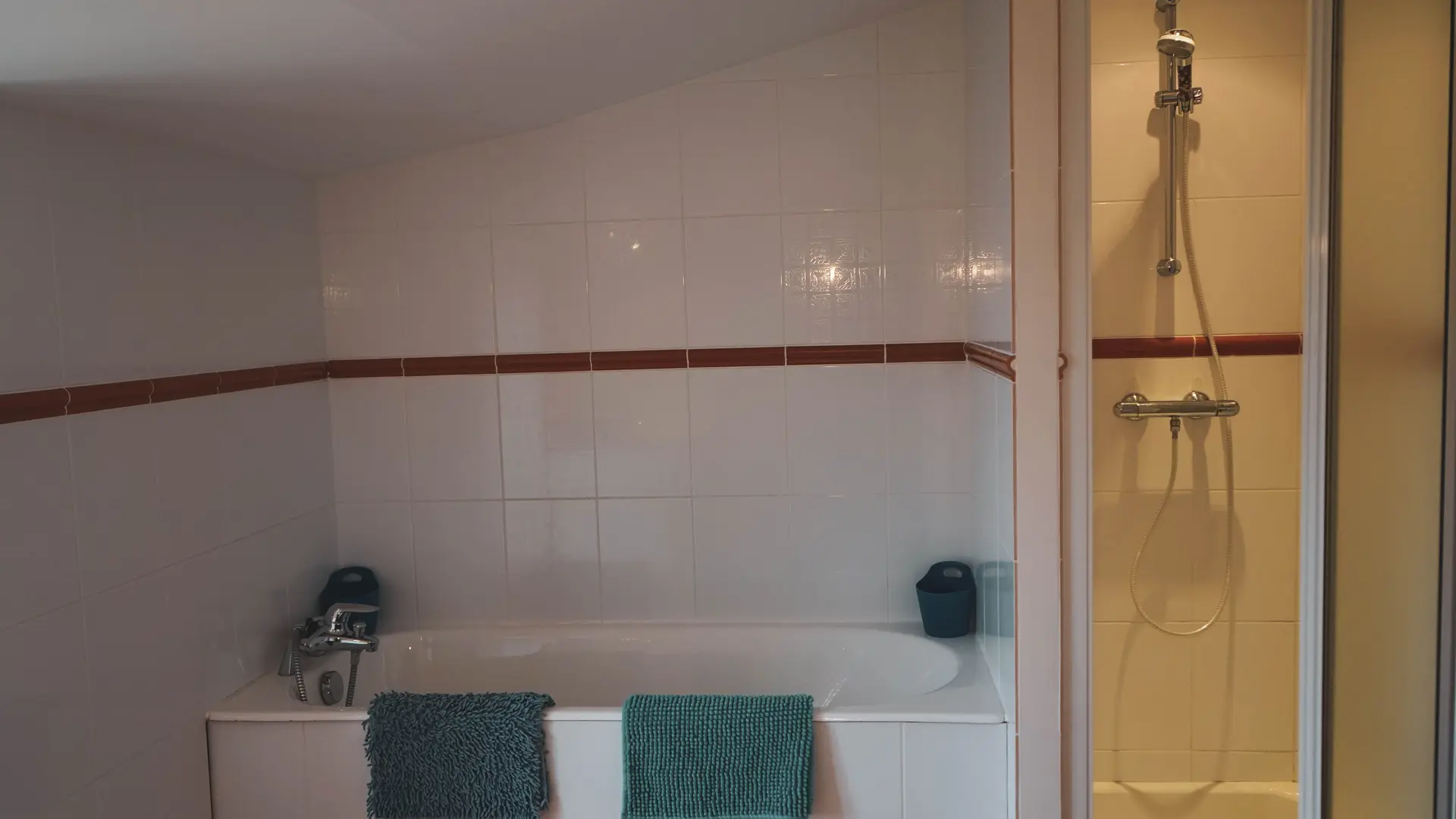 La salle de bain des Fillattes avec sa baignoire et sa douche et sa grande étagère à droite