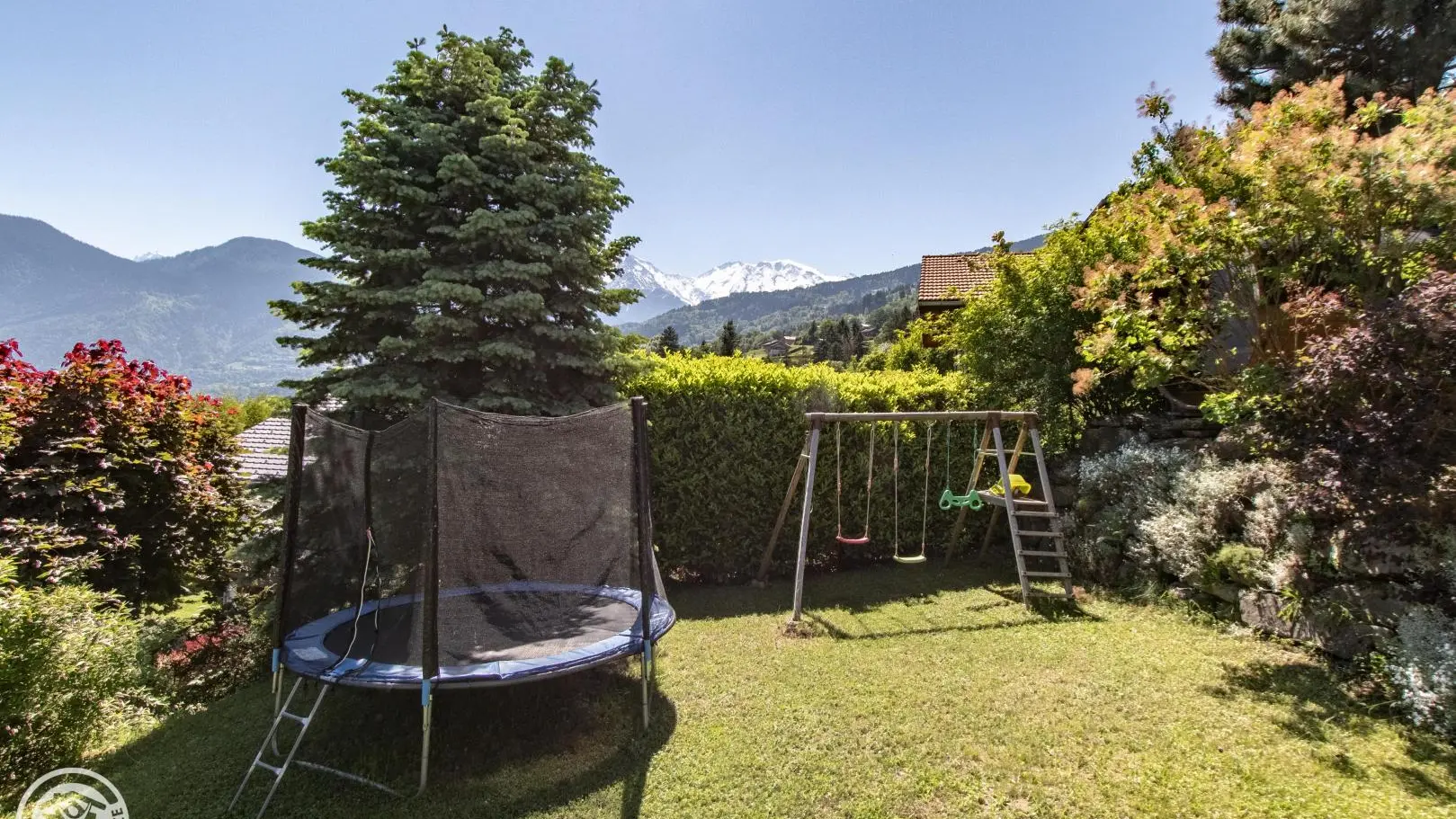 Le jardin avec trampoline, portique et sauna panoramique.