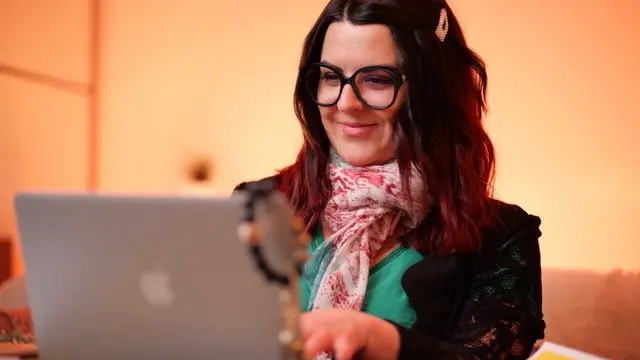 Une femme souriante travaille devant un ordinateur portable