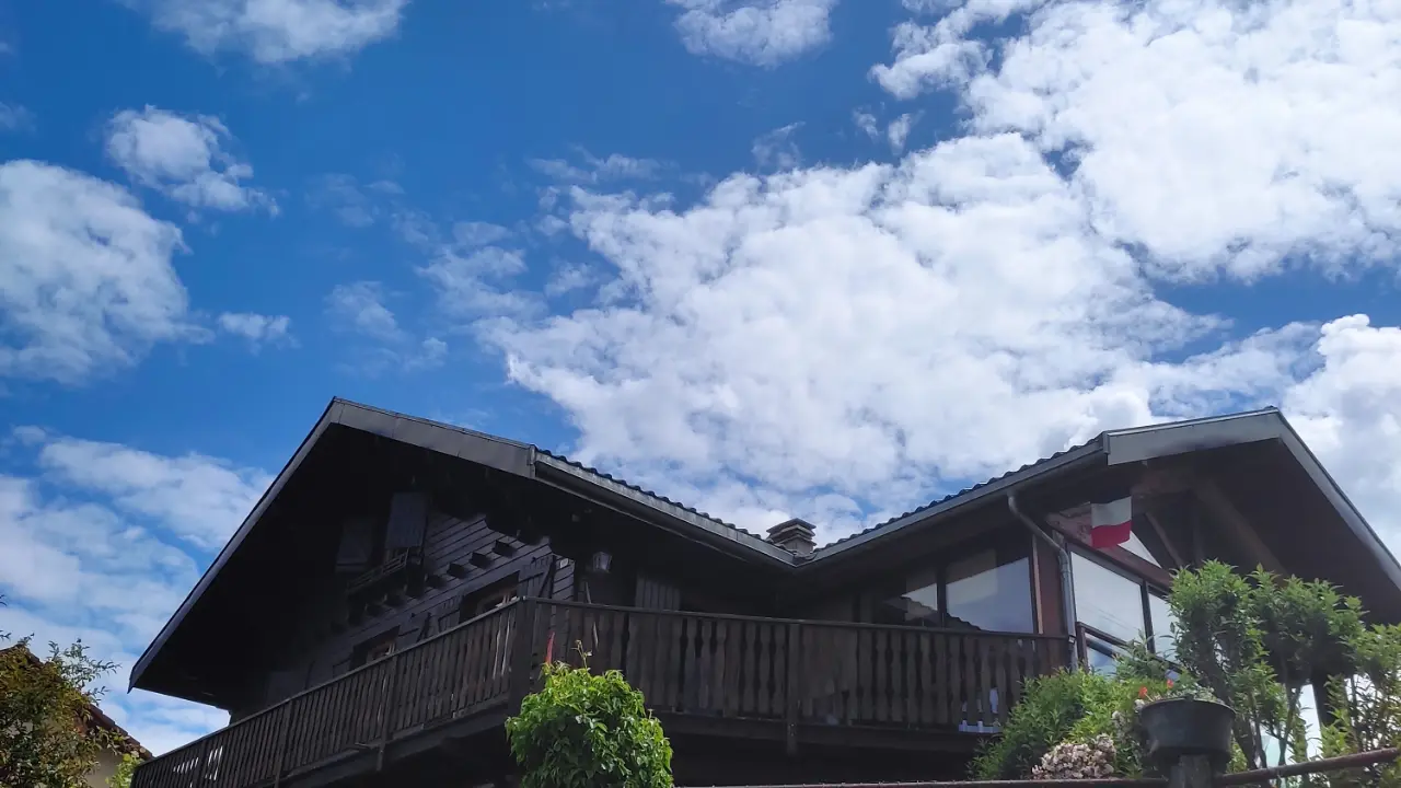 Nichée dans un écrin de verdure, cette maison arbore une architecture traditionnelle de chalet.