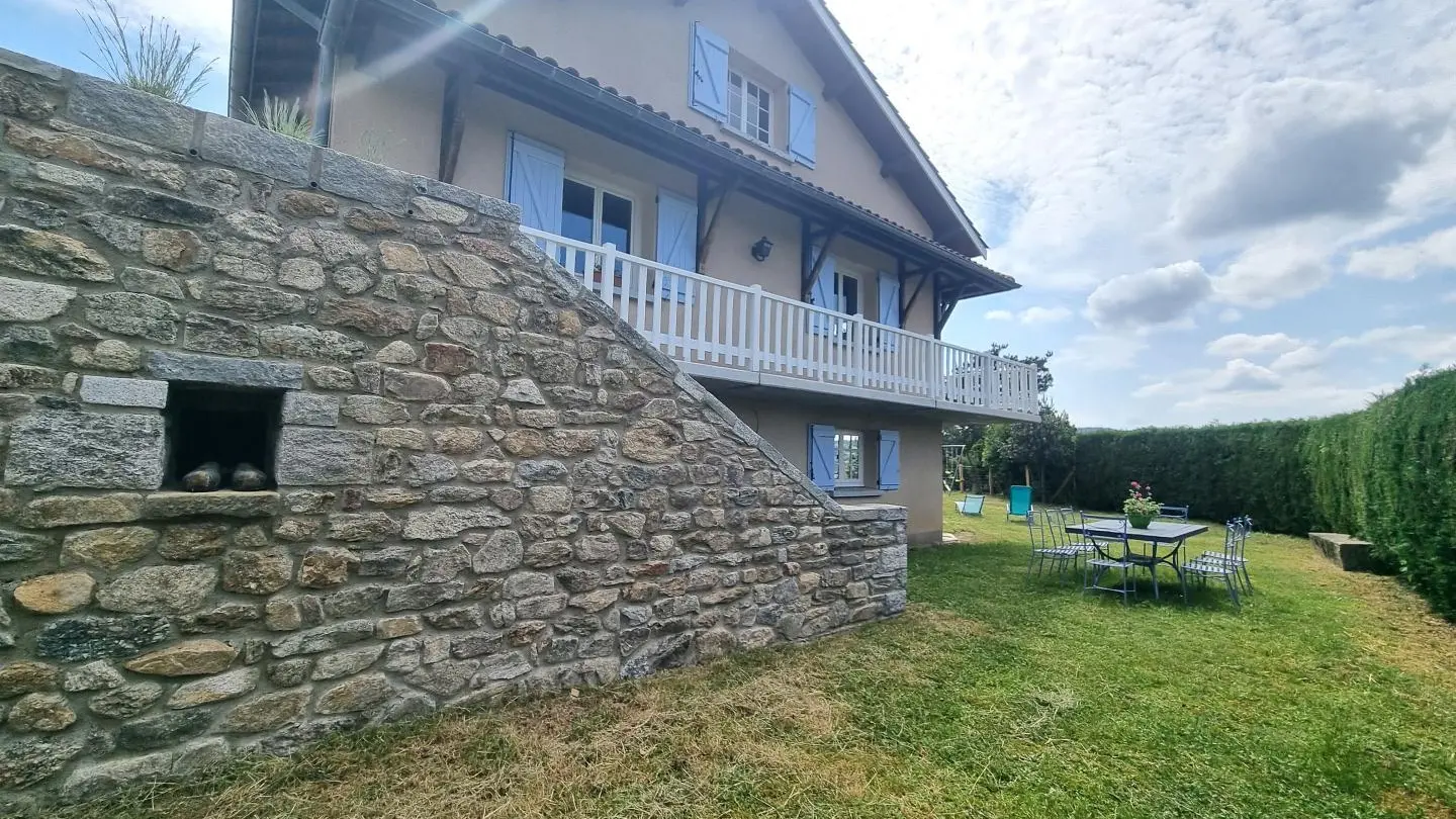 Façade Ouest du gîte avec son salon de jardin et son barbecue.