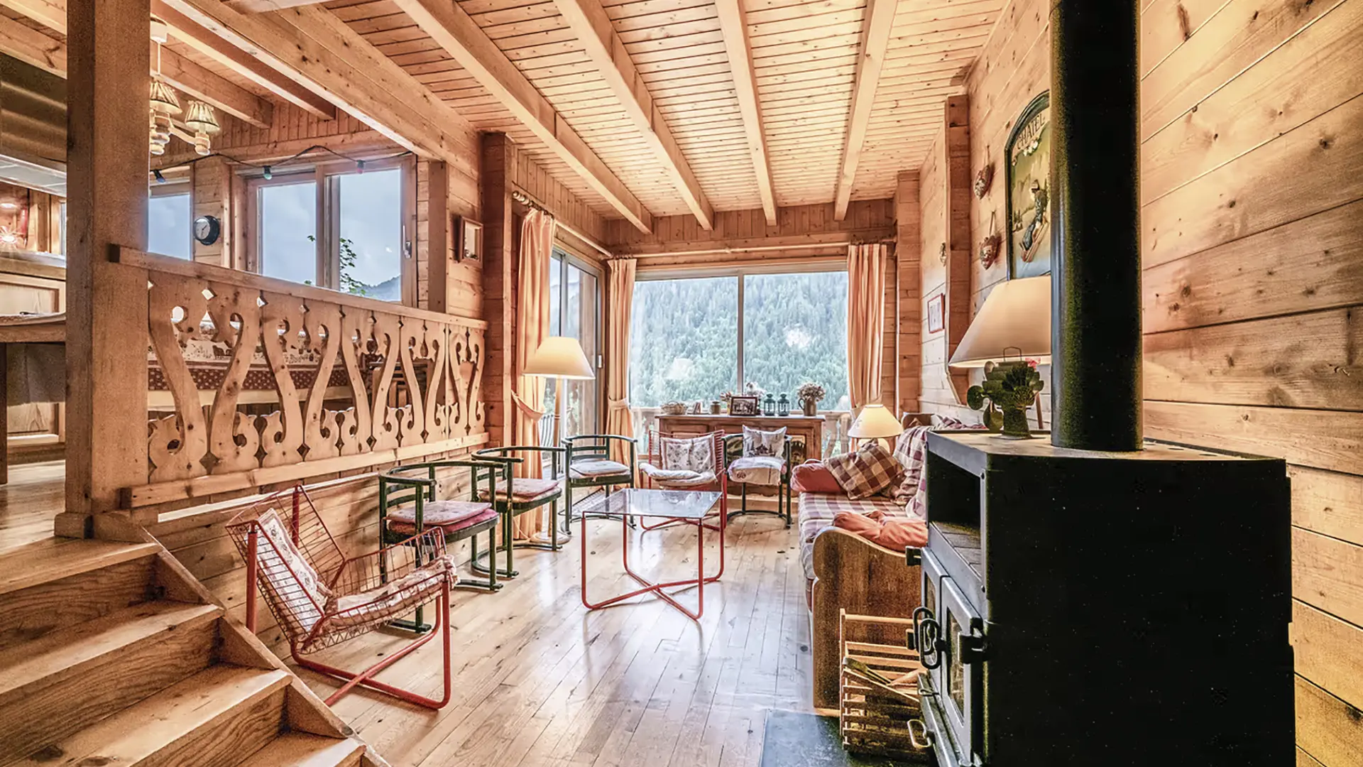Salon avec poele à bois, canapé, fauteuils, table basse, baie vitrée