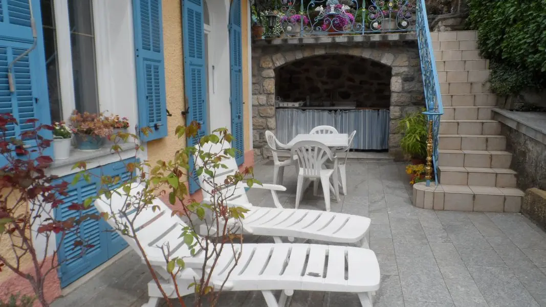 La terrasse privée avec la cuisine d'été au fond, l'accès au jardinet avec chaises longues