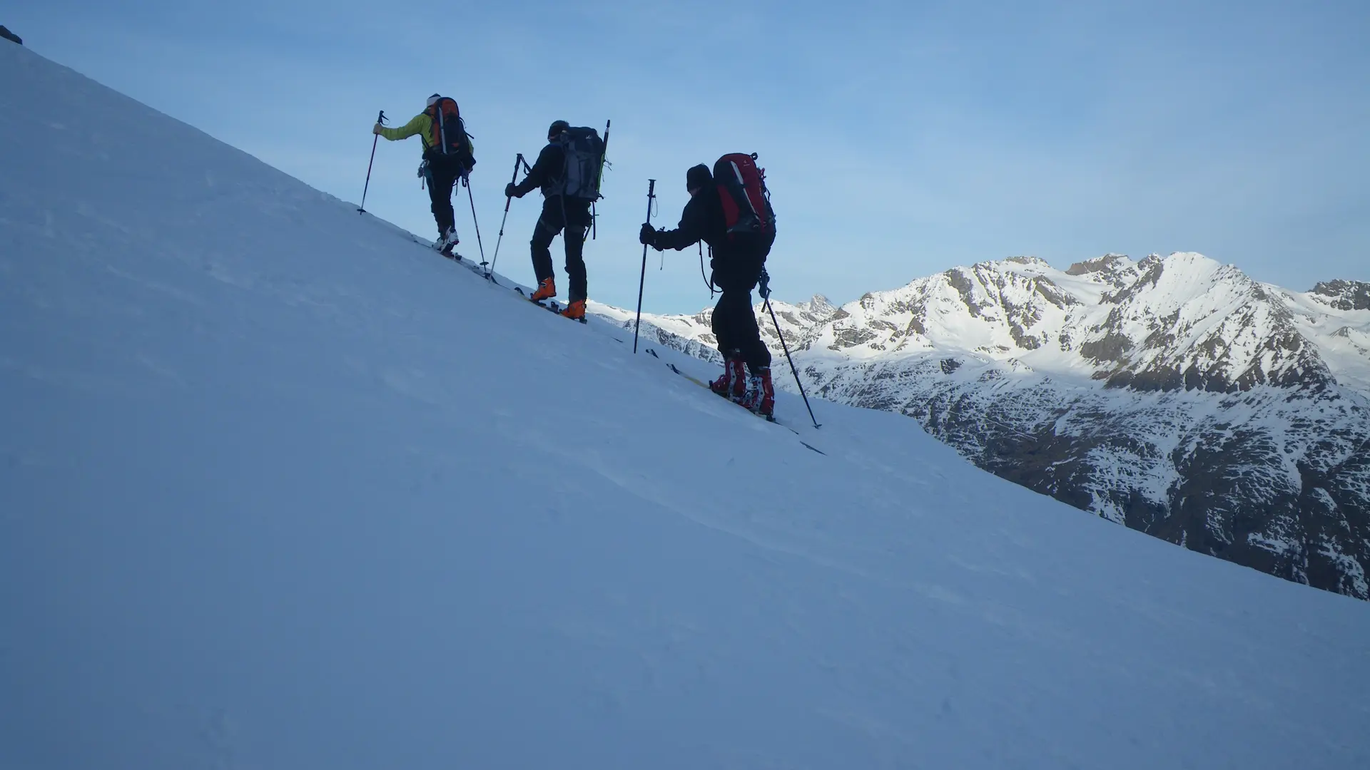 vue de dos de 3 skieurs de randonnée en montée