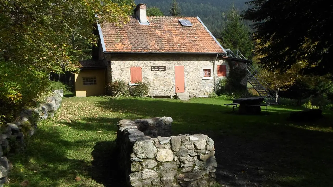 Le refuge est une petite maison de campagne, construite en pierre et dotée d'un toit pentu. Elle est située dans un endroit calme et entouré de nature, avec des arbres et des plantes. Devant la maison, il y a un petit espace ouvert, faisant office de jardin.