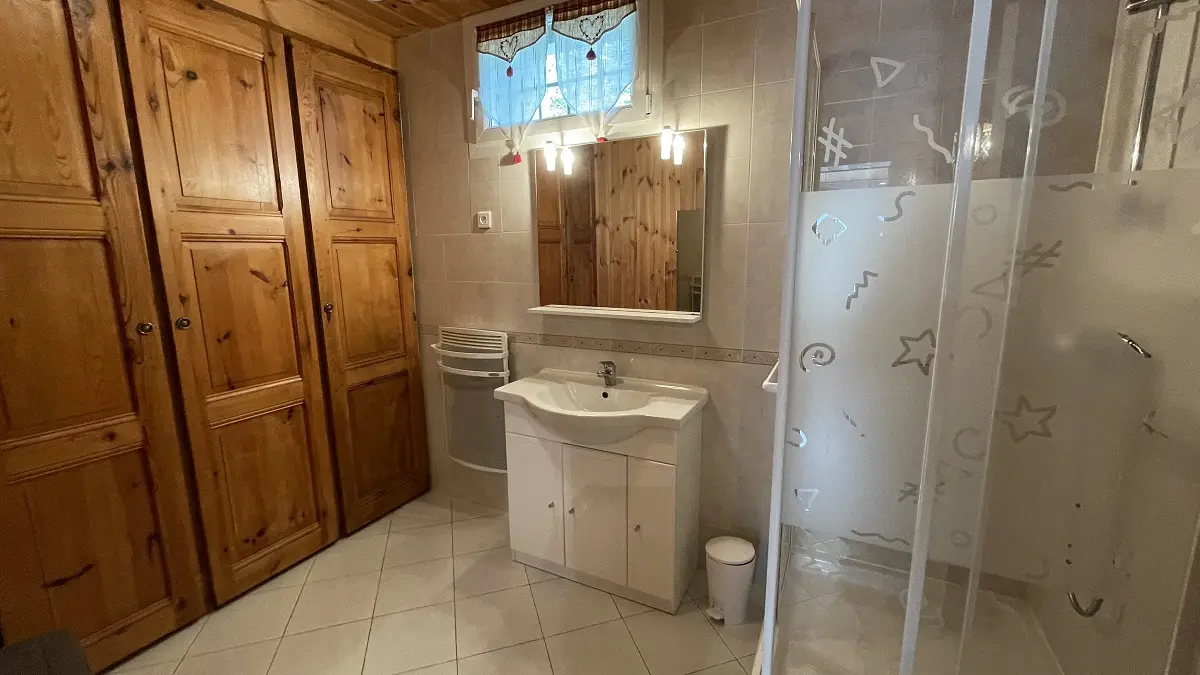 Salle de bains lumineuse carrelée avec bac à douche, ameublement bois, fenêtre