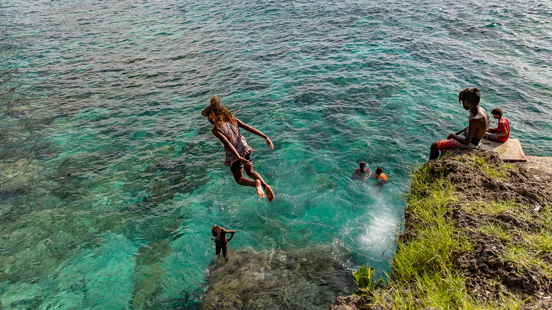 Children jumping into the sea