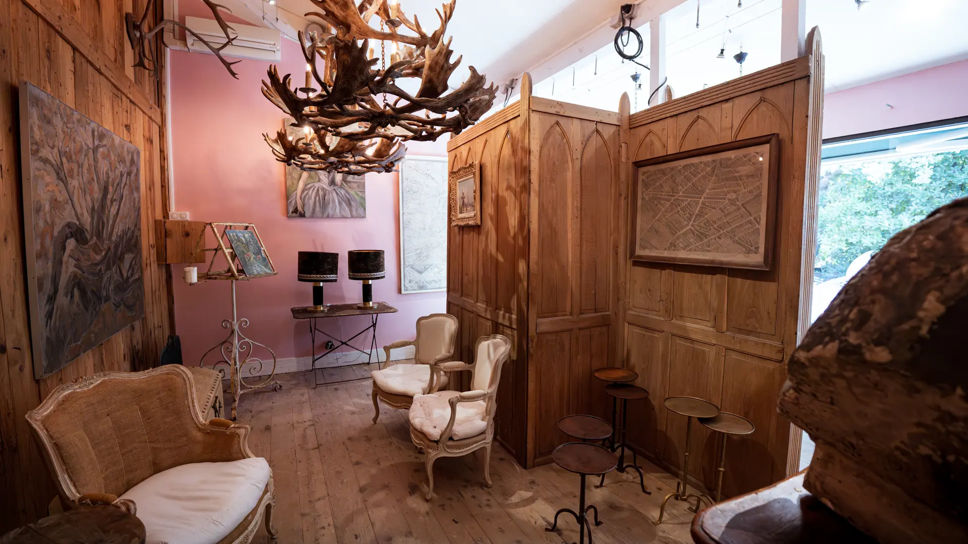 Un espace mêlant bois brut, fauteuils anciens et luminaires sculpturaux crée une atmosphère chaleureuse et artisanale.