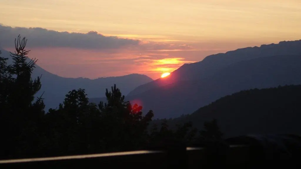 Un paysage avec le soleil se couchant derrière les montagnes.