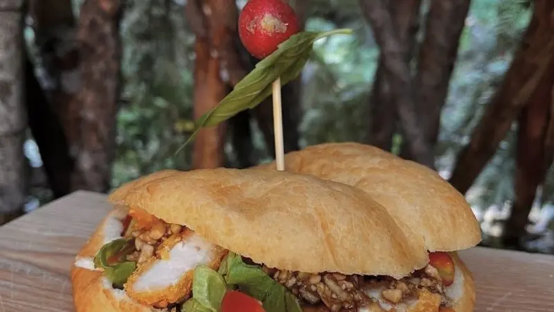 Sandwich avec poulet pané, salade, petite tomate, cacahuète