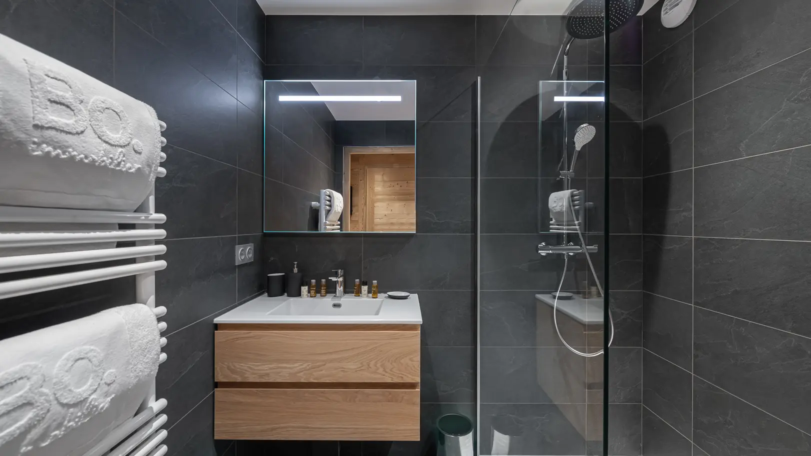 Salle de bains avec douche, vasque avec son meuble, miroir, sèche serviettes