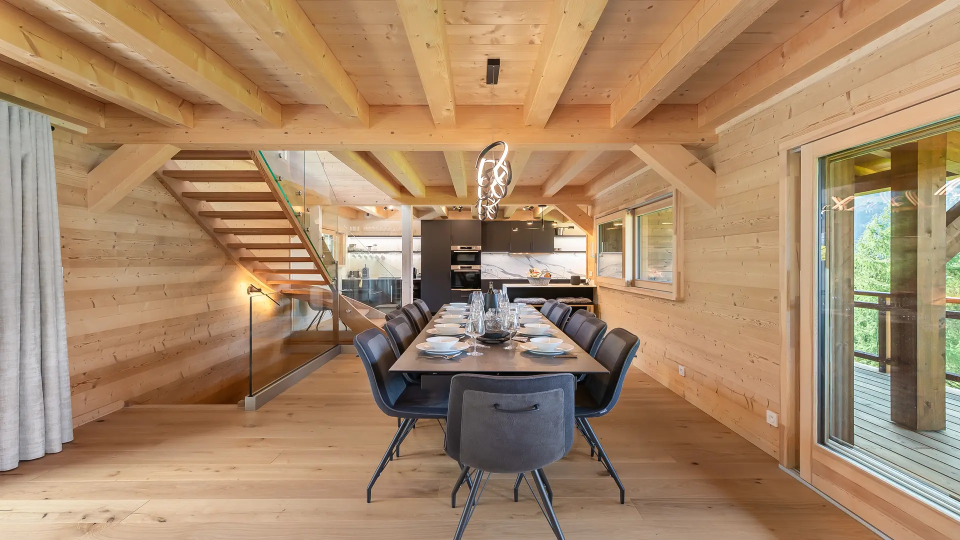 Grande salle à manger à côté de la cuisine, baie vitrée donnant accès au balcon et vue sur les montagnes et le village
