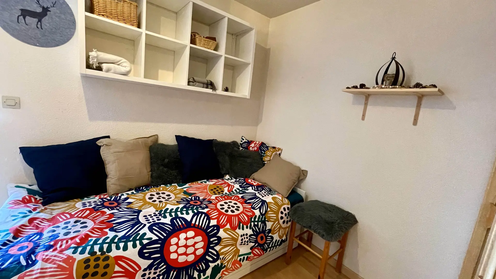 Coin salon avec son canapé convertible, ses coussins, étagères et déco murales